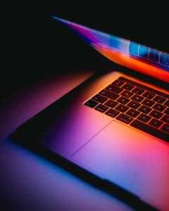 Macbook is partially open on table. Macbook is partially open on table.