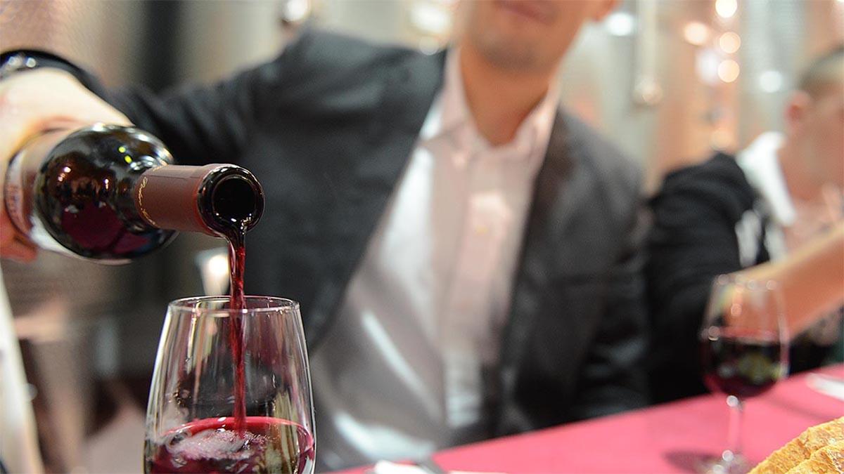 Man pours red wine at gala
