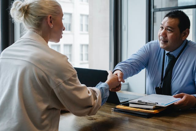 woman shakes hands with man across table in office