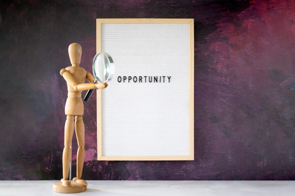 A wooden figure pointing to a white board with the word 'opportunity' written on it