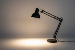 Adjustable desk lamp refocused to cast new light on a neutral background, symbolizing an adaptive coaching approach.