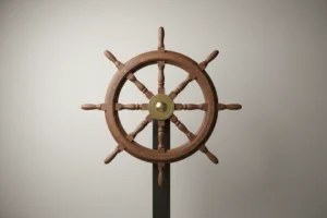 Single wooden ship’s wheel on a soft neutral background, warm light highlighting the brass hub.