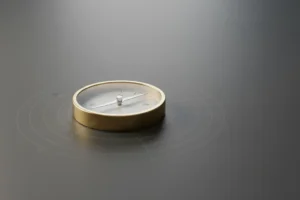 Minimalist brass compass on a matte slate surface, softly lit, with subtle radial lines suggesting a guiding company value.
