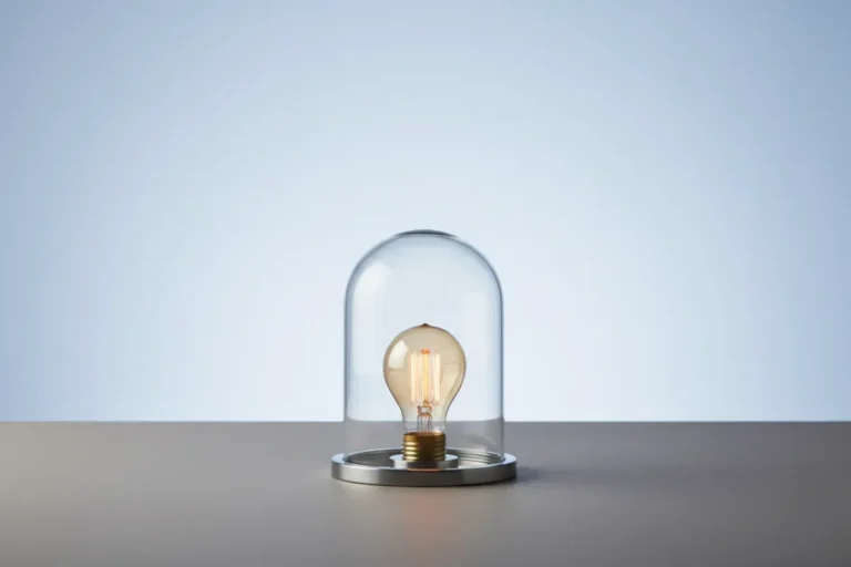 Glowing lightbulb under a glass dome on a neutral background, symbolizing protected ideas and intellectual property.