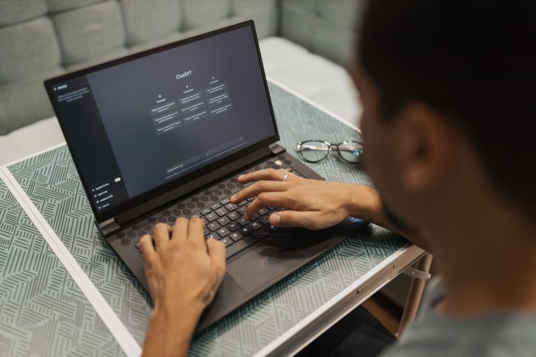 A person sits at a desk, looking at a screen with charts and text, indicating business planning aided by AI