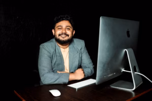 Confident businessman sitting at desk, working on computer in modern office.