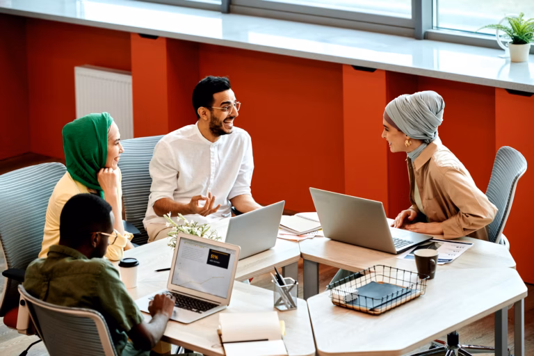 A diverse group of professionals collaborates around a table in a bright, modern office