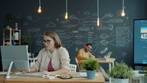 A person thoughtfully reviews data on a tablet, surrounded by modern office technology