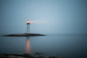 Minimal lighthouse in fog casting a warm beam over calm water, symbolizing clear, steady leadership guidance.