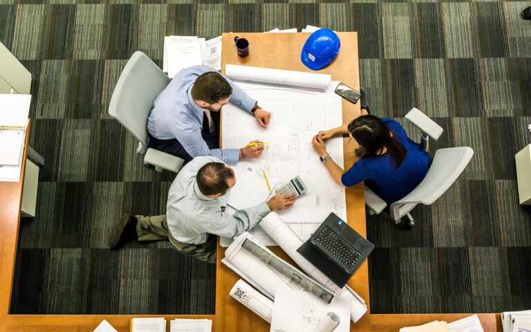 A diverse group of business professionals in a modern office setting discusses data on a screen