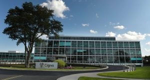 The Cigna Group headquarters building in Bloomfield, Connecticut, behind a large tree and a curved driveway.