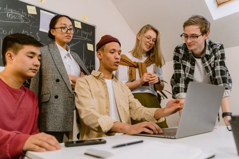 Students working together on a laptop project in a classroom