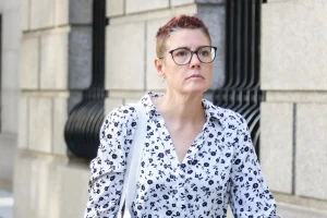 Christine Hunsicker wearing glasses and a floral shirt outside a stone building