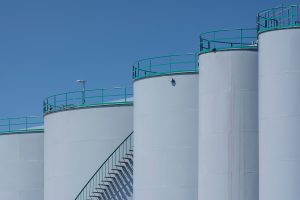 Industrial storage tanks beneath a blue sky; illustrative petroleum-industry photo