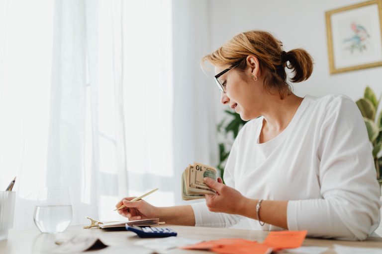 Woman reviewing cash and a calculator at a desk