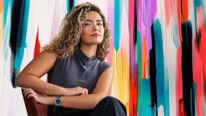 Kalder founder Gökçe Güven seated in front of a colorful painted wall
