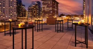 Rooftop terrace with cocktail tables and candles overlooking a city skyline at dusk