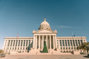Front view of Oklahoma State Capitol adorned with a Christmas tree, under clear skies