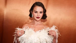 Selena Gomez wearing a white feathered dress against an orange background
