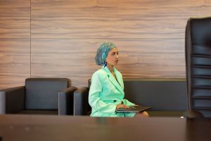 Businesswoman in a mint blazer sitting with a laptop in an office environment